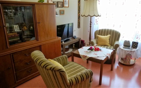 kleines Wohnzimmer mit zwei Sesseln, Couchtisch und Wandschrank